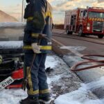 Equipe de bombeiros próximos ao carro, após conter as chamas.